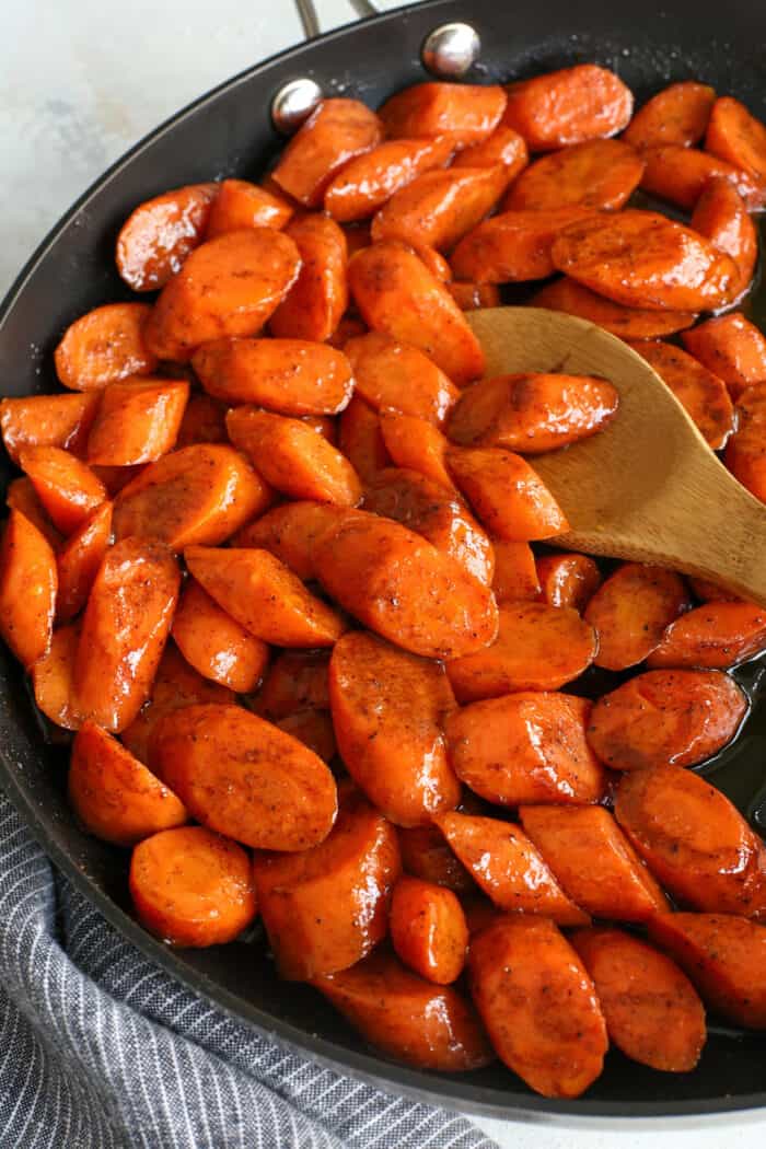 A wooden spoon stirring glazed carrots