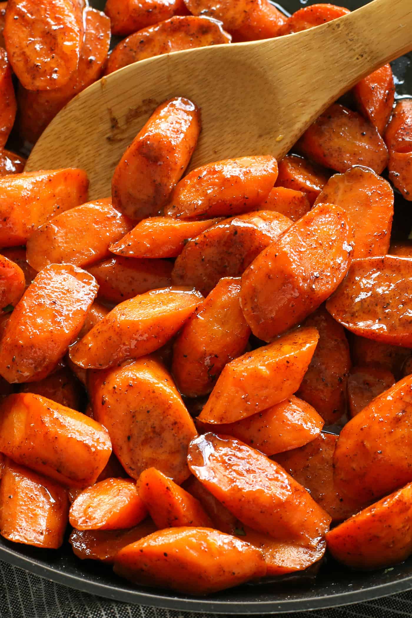 Close up of a spoon stirring honey glazed carrots