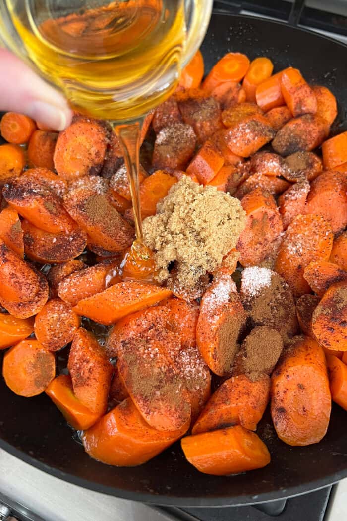 pouring honey over cut carrots