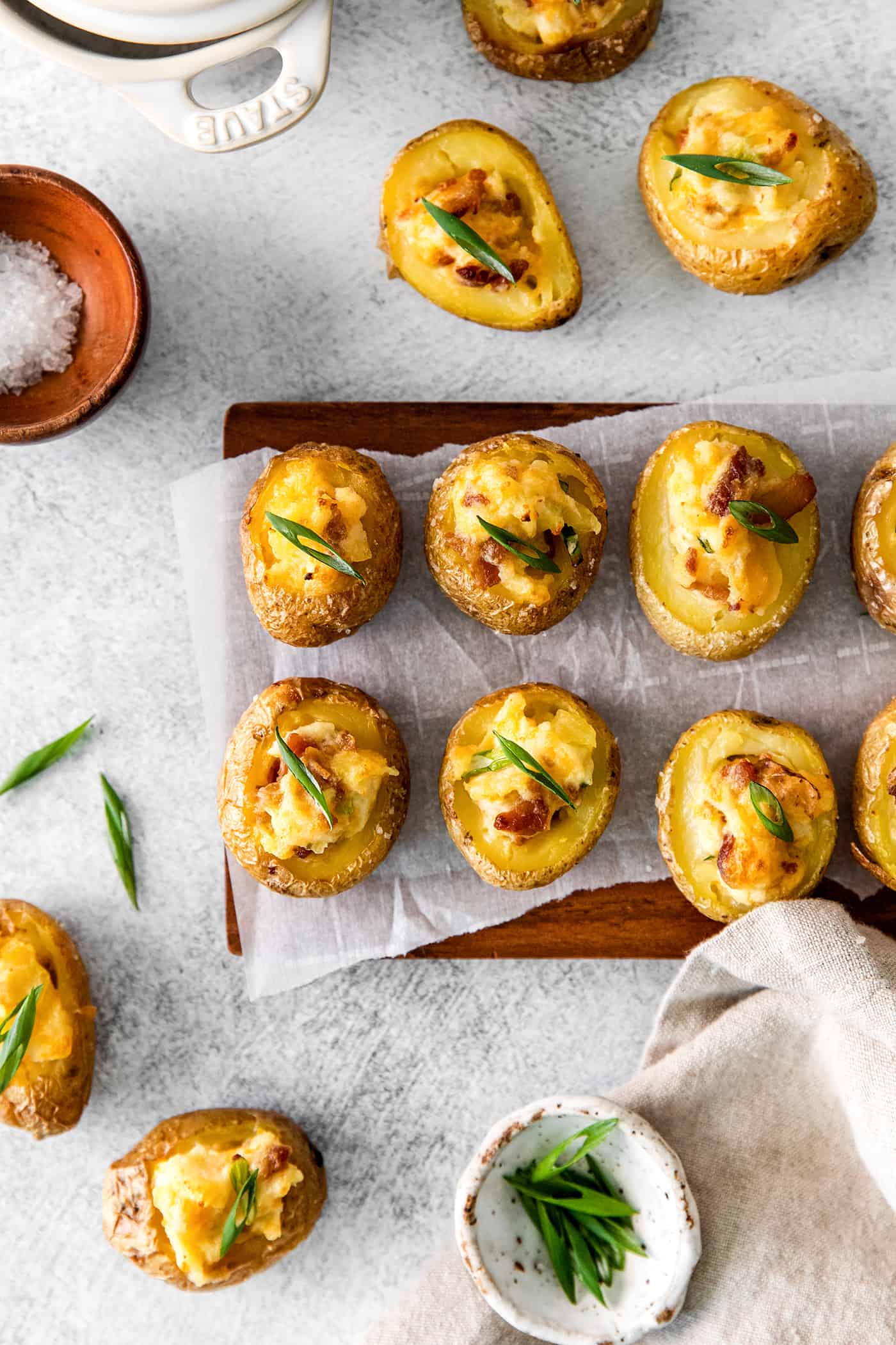 Overhead view of 6 mini baked potatoes on parchment paper on a cutting board