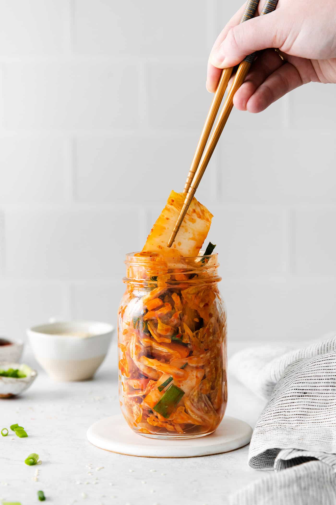 Chopsticks diving into a glass jar of kimchi