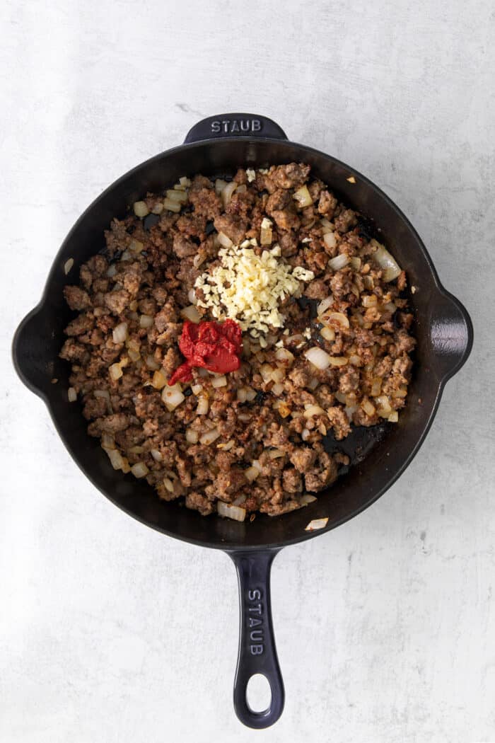 Ground sausage, onion, garlic, and tomato paste in a skillet