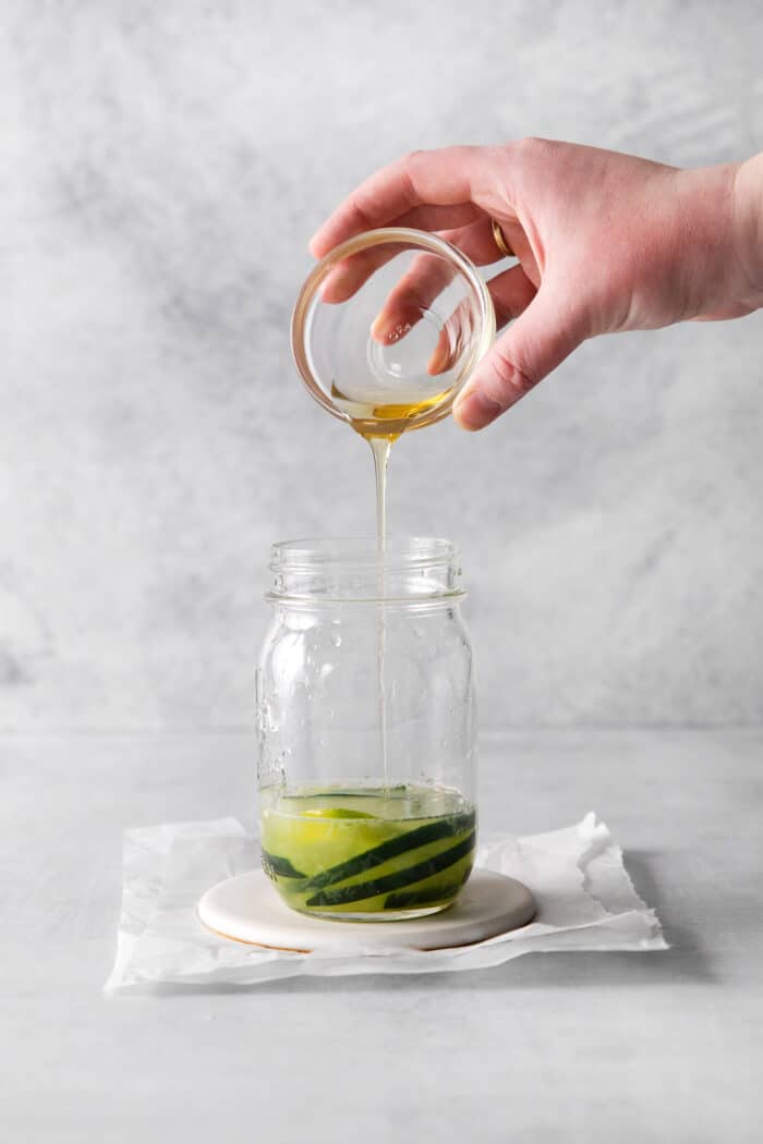 Agave being poured into muddled cucumber slices