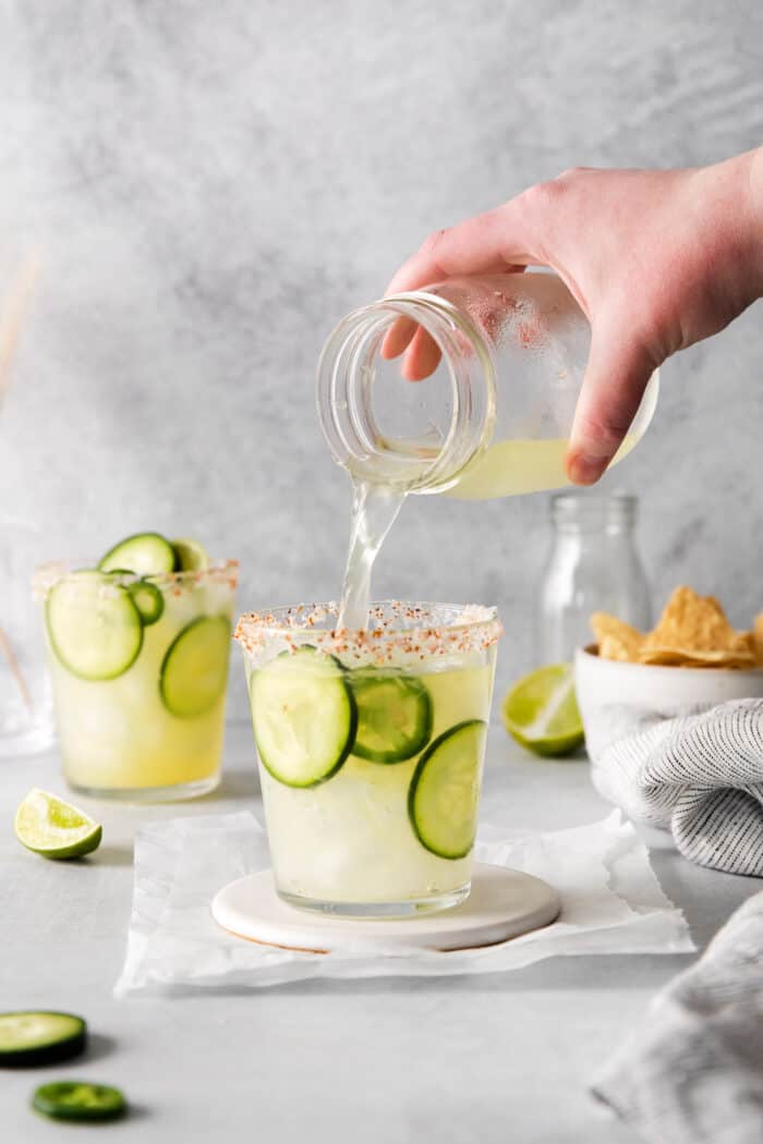Spicy cucumber margarita being poured into a glass