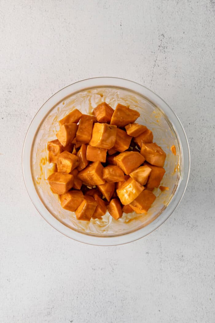 A bowl of sweet potato cubes coated with peanut sauce