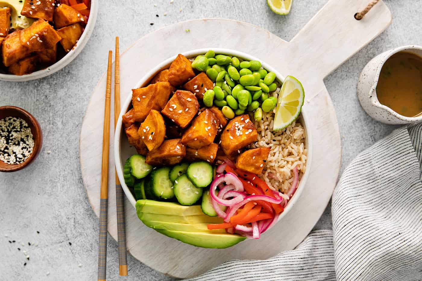Overhead view of a vegetarian poke bowl on a white plate with chopsticks