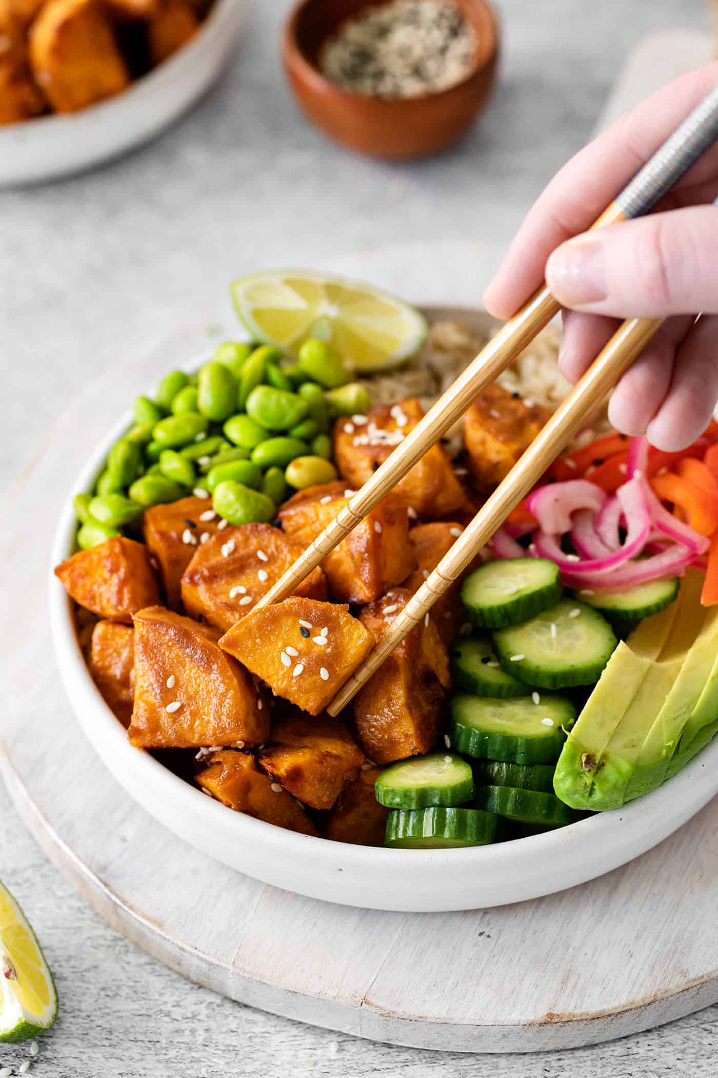 Chopsticks going for a piece of sweet potato in a vegetarian poke bowl