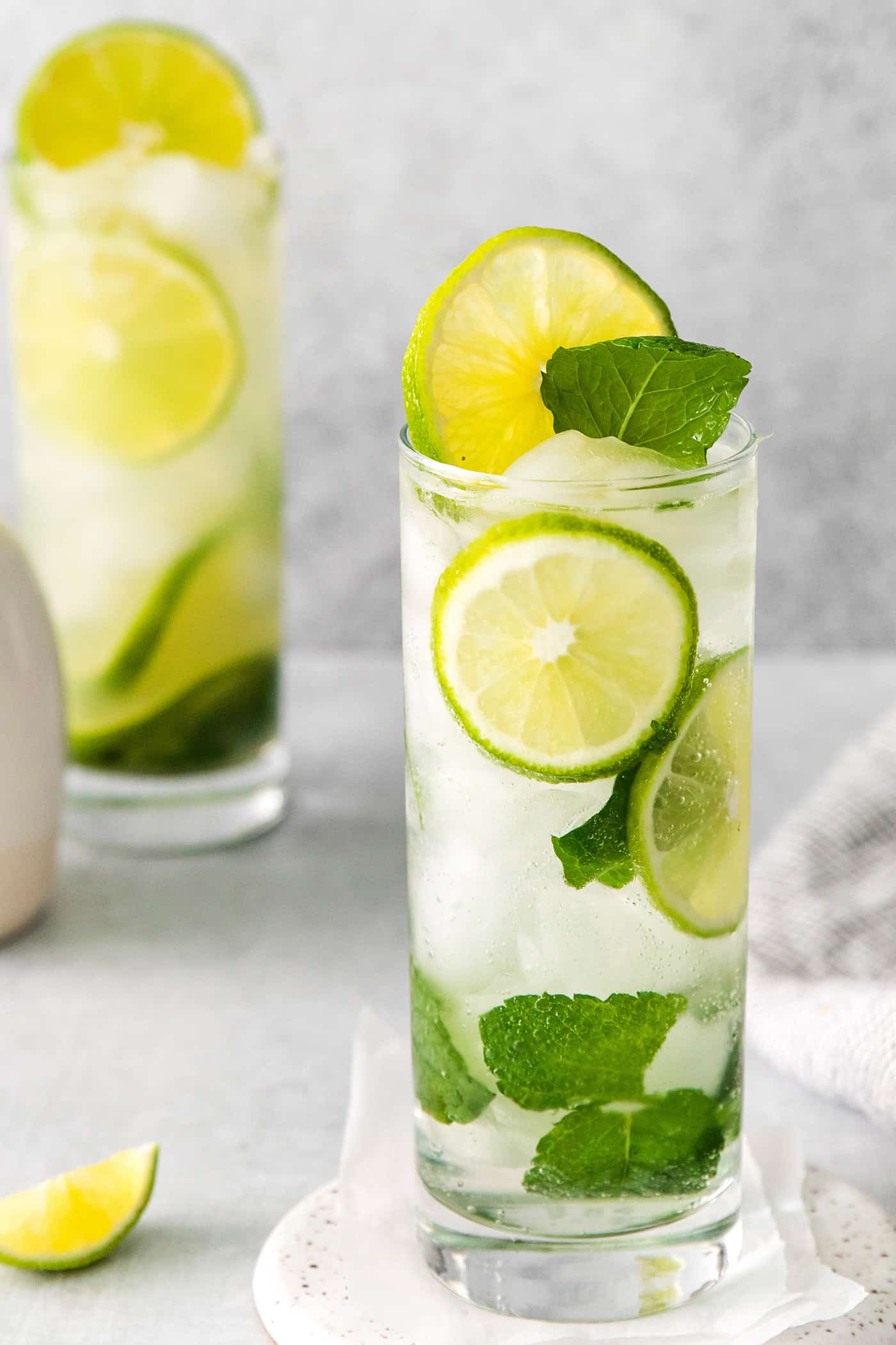 Two mojitos with tequila and lime in tall glasses