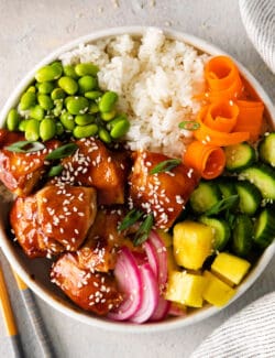 overhead view of a teriyaki chicken poke bowl with rice, edadame and veggies