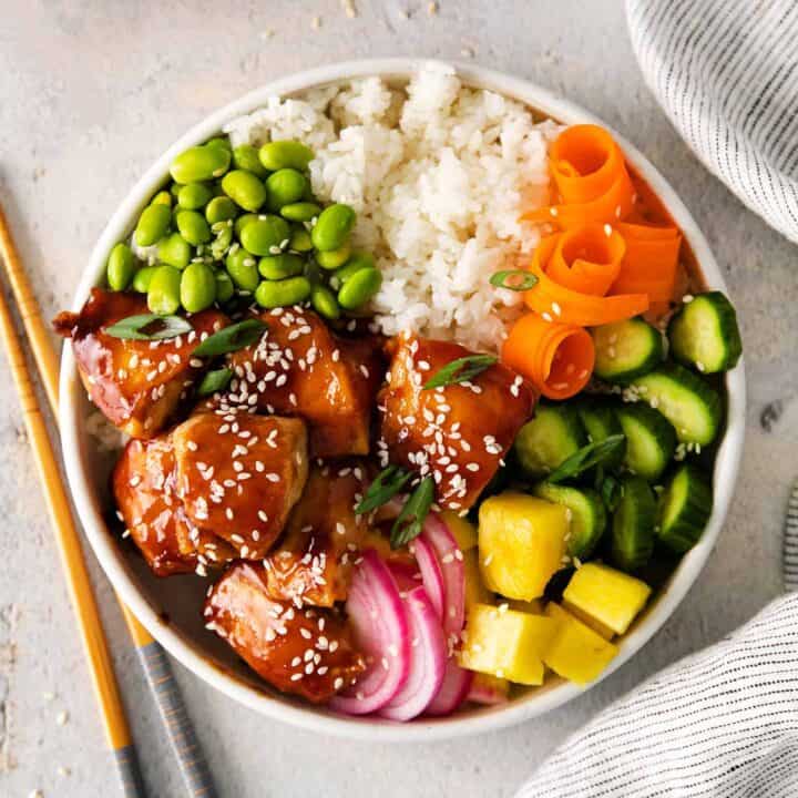 overhead view of a teriyaki chicken poke bowl with rice, edadame and veggies