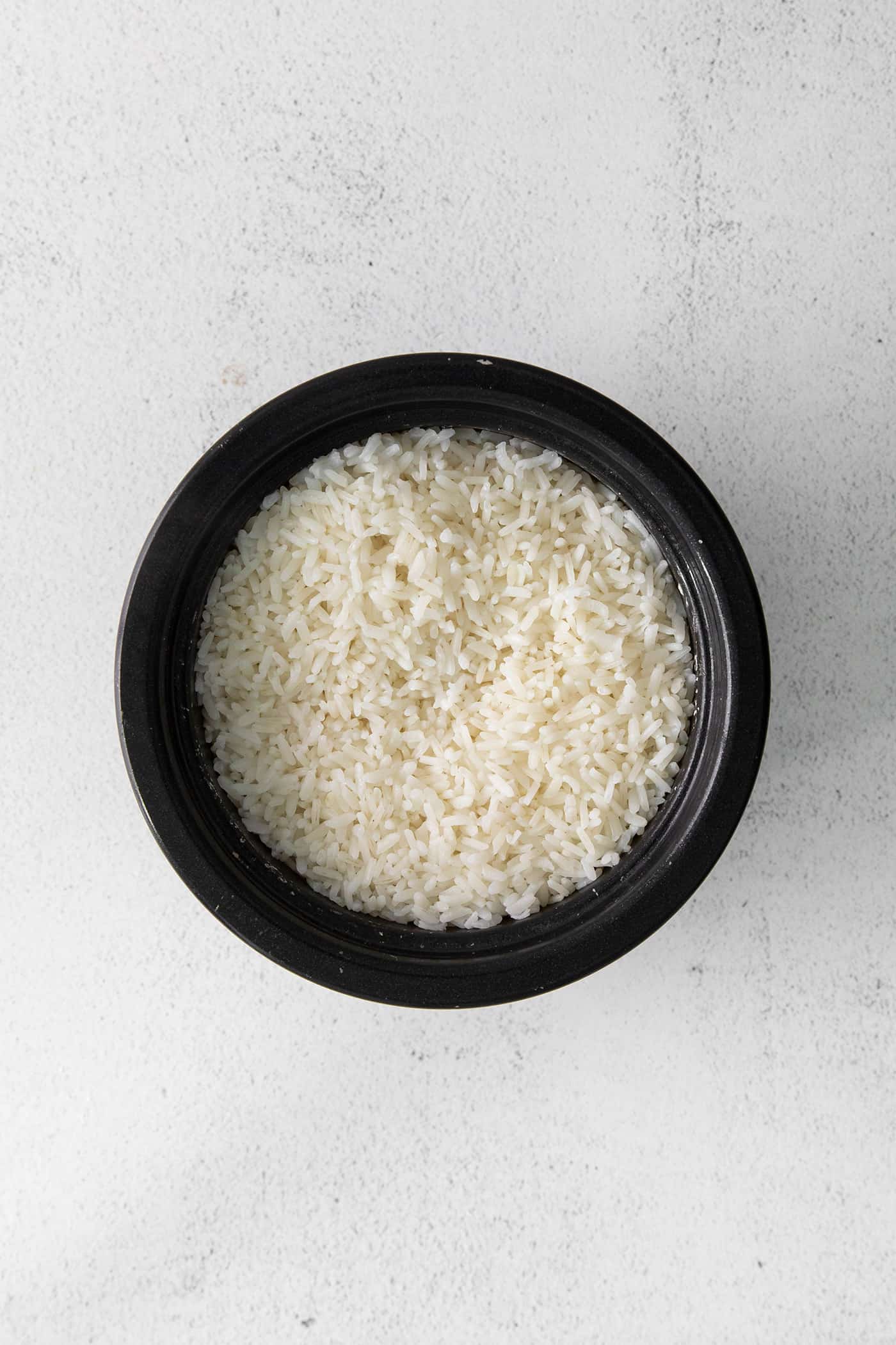Cooked sushi rice in a black dish