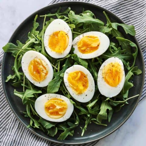 Air fryer hardboiled eggs on a bed of arugula