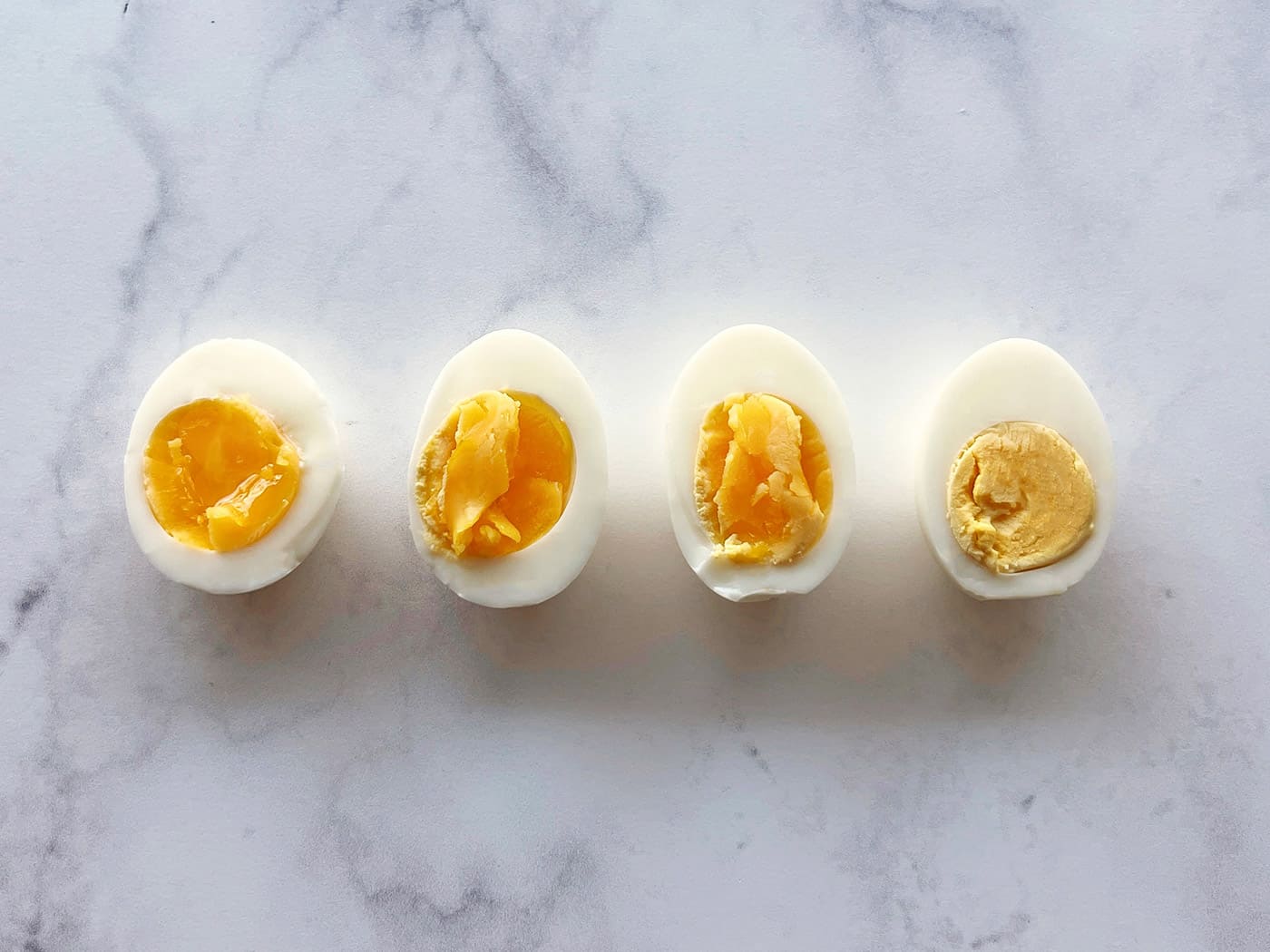 4 hard boiled eggs cut in half, showing different levels of doneness