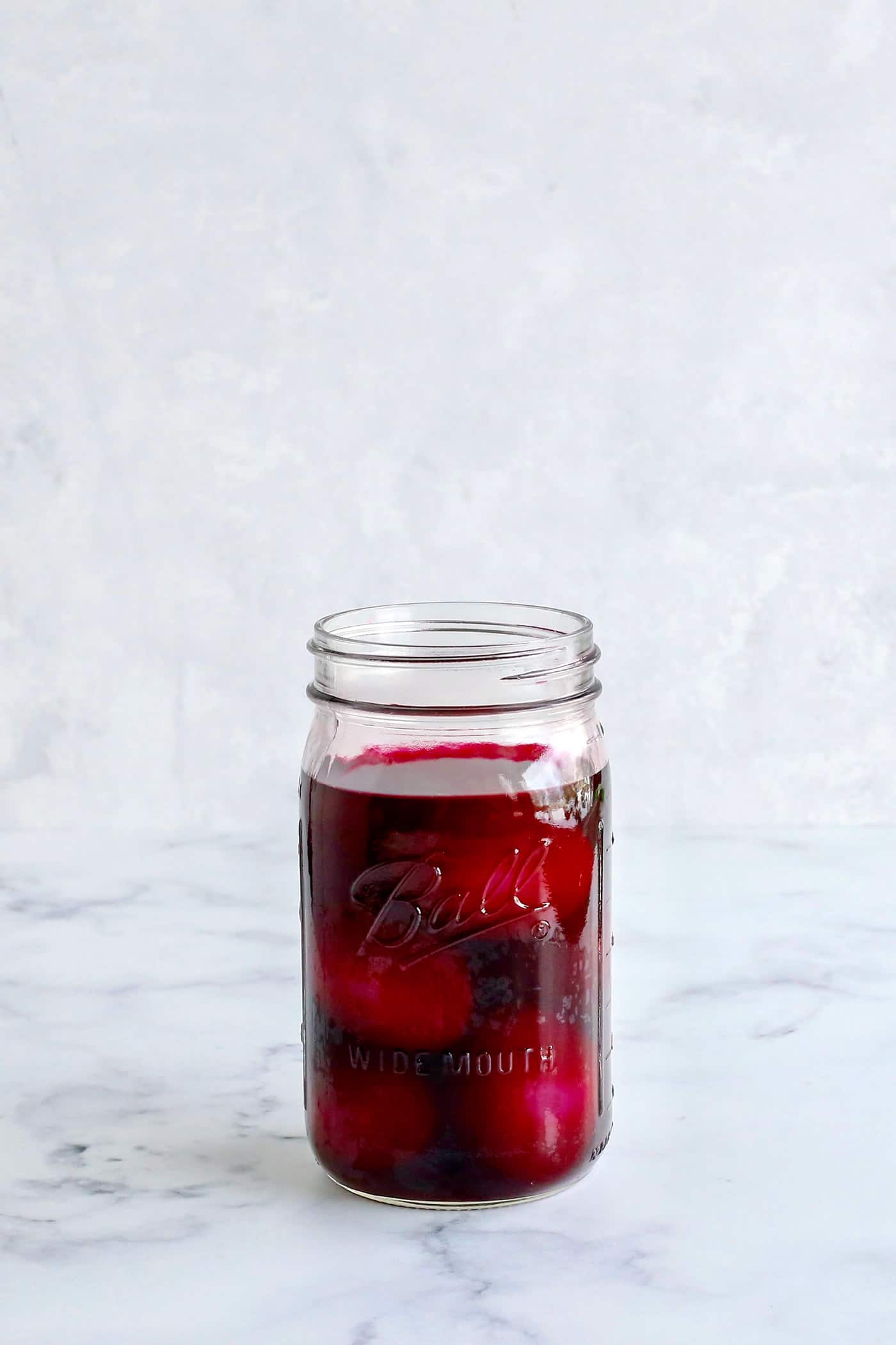 A mason jar of hard boiled eggs with pickled beet juice