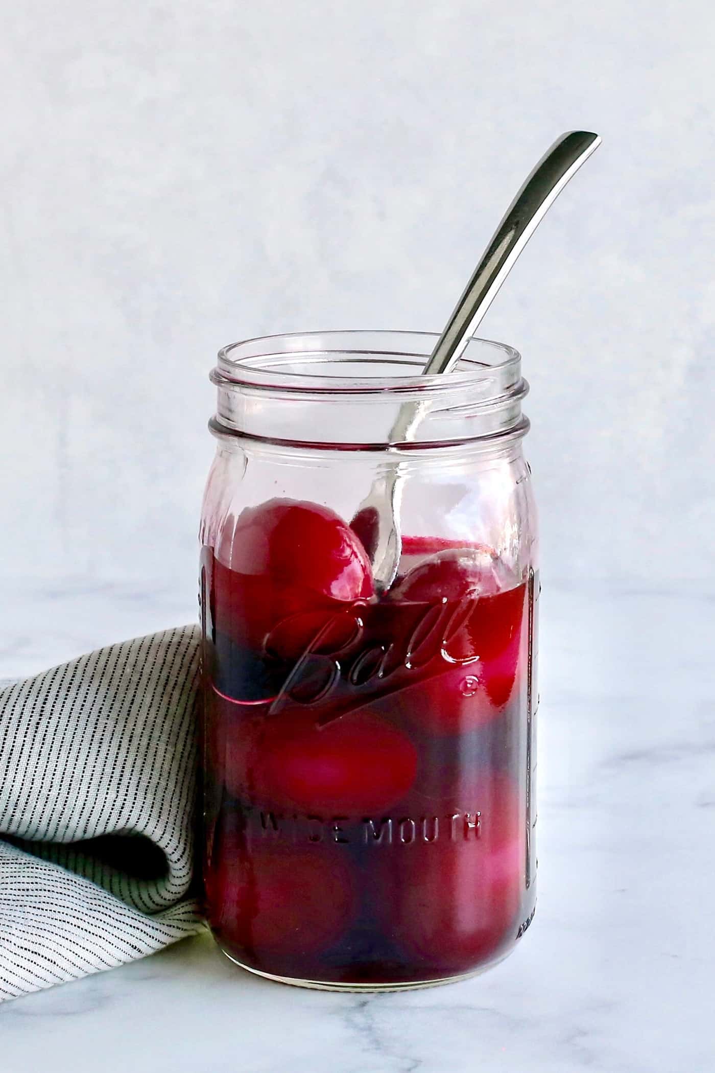 A jar of beet pickled eggs with a spoon