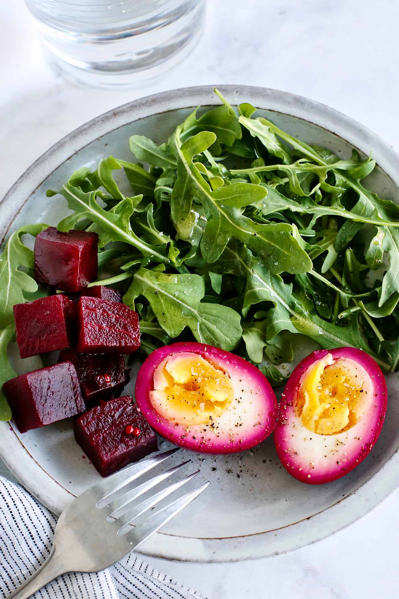 A plate with beet pickled eggs, pickled beets, and salad