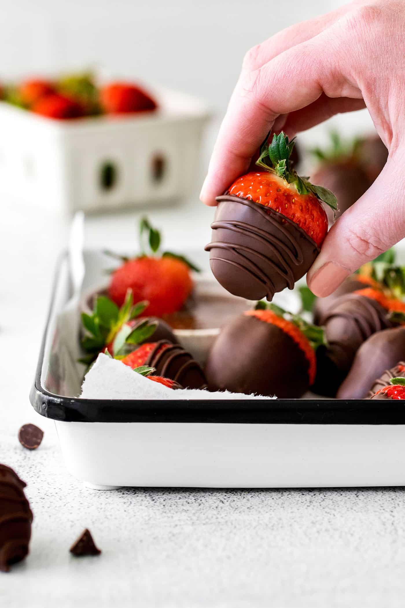 A hand holding a chocolate covered strawberry