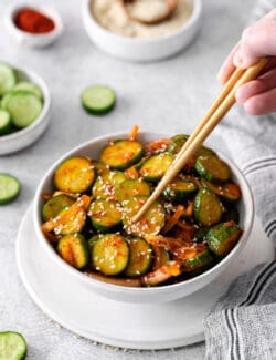 Chopsticks grabbing cucumber kimchi from a bowl