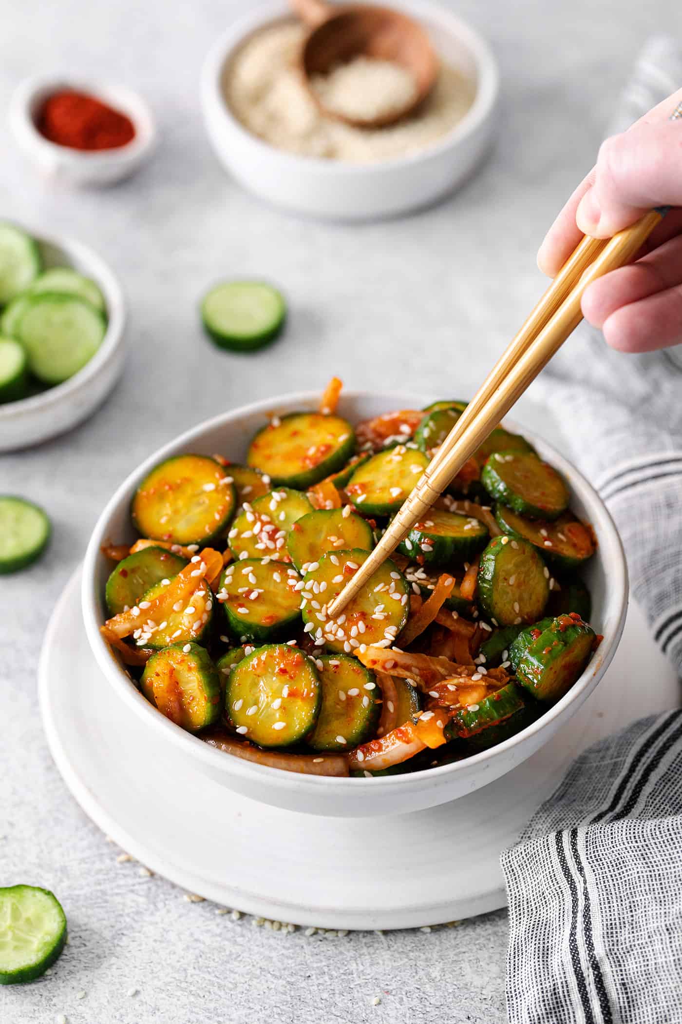 Chopsticks grabbing cucumber kimchi from a bowl