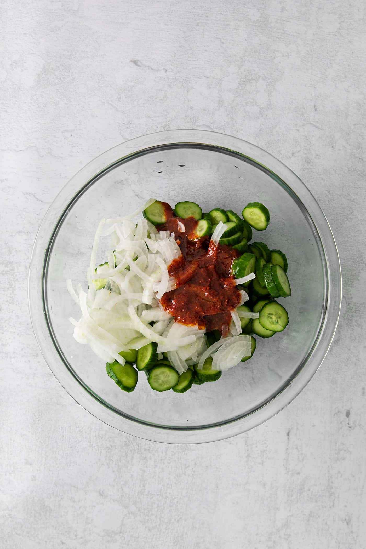 Cucumber slices, white onions, and kimchi sauce in a dish
