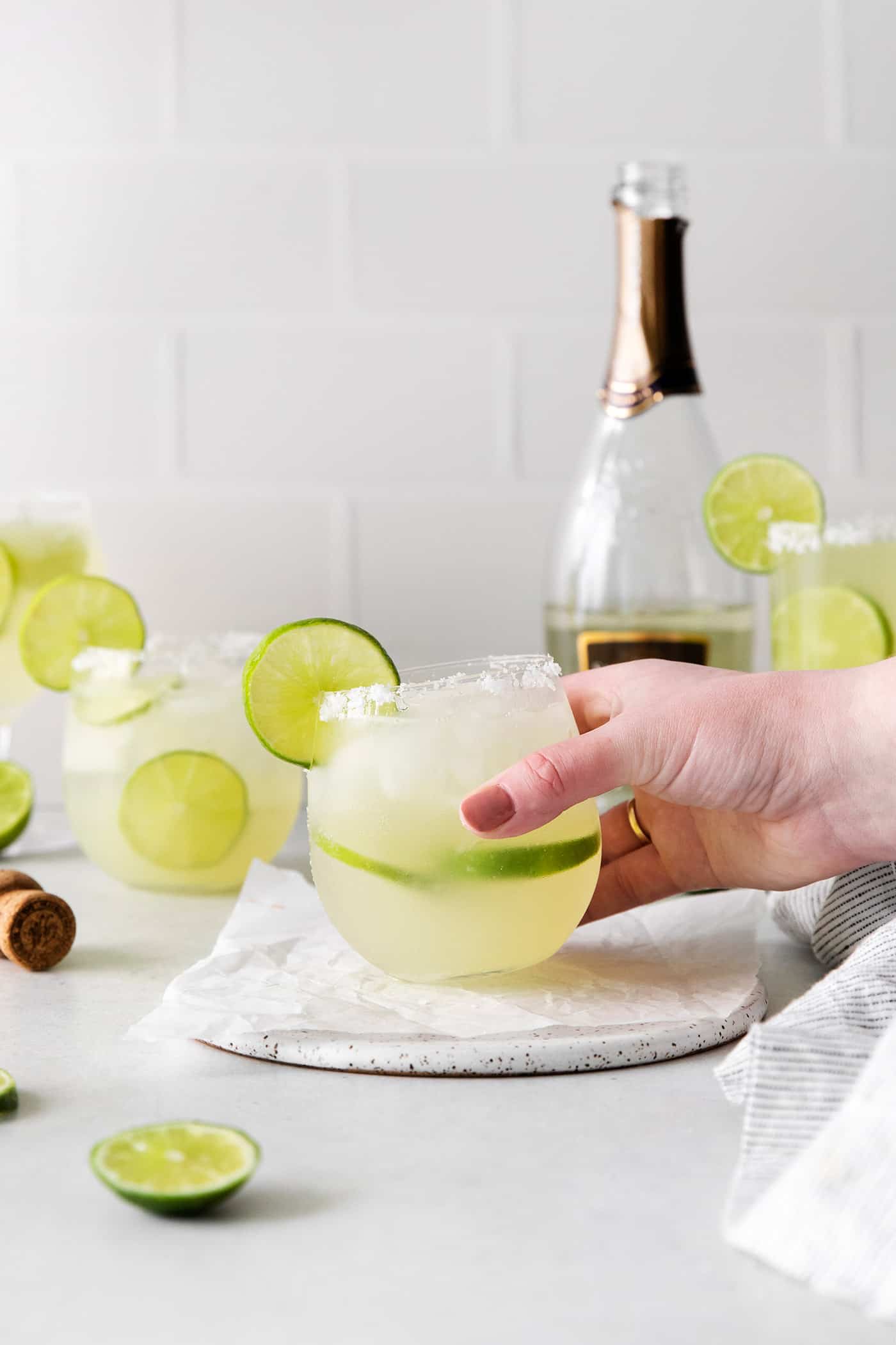 a hand holding a glass of prosecco margarita