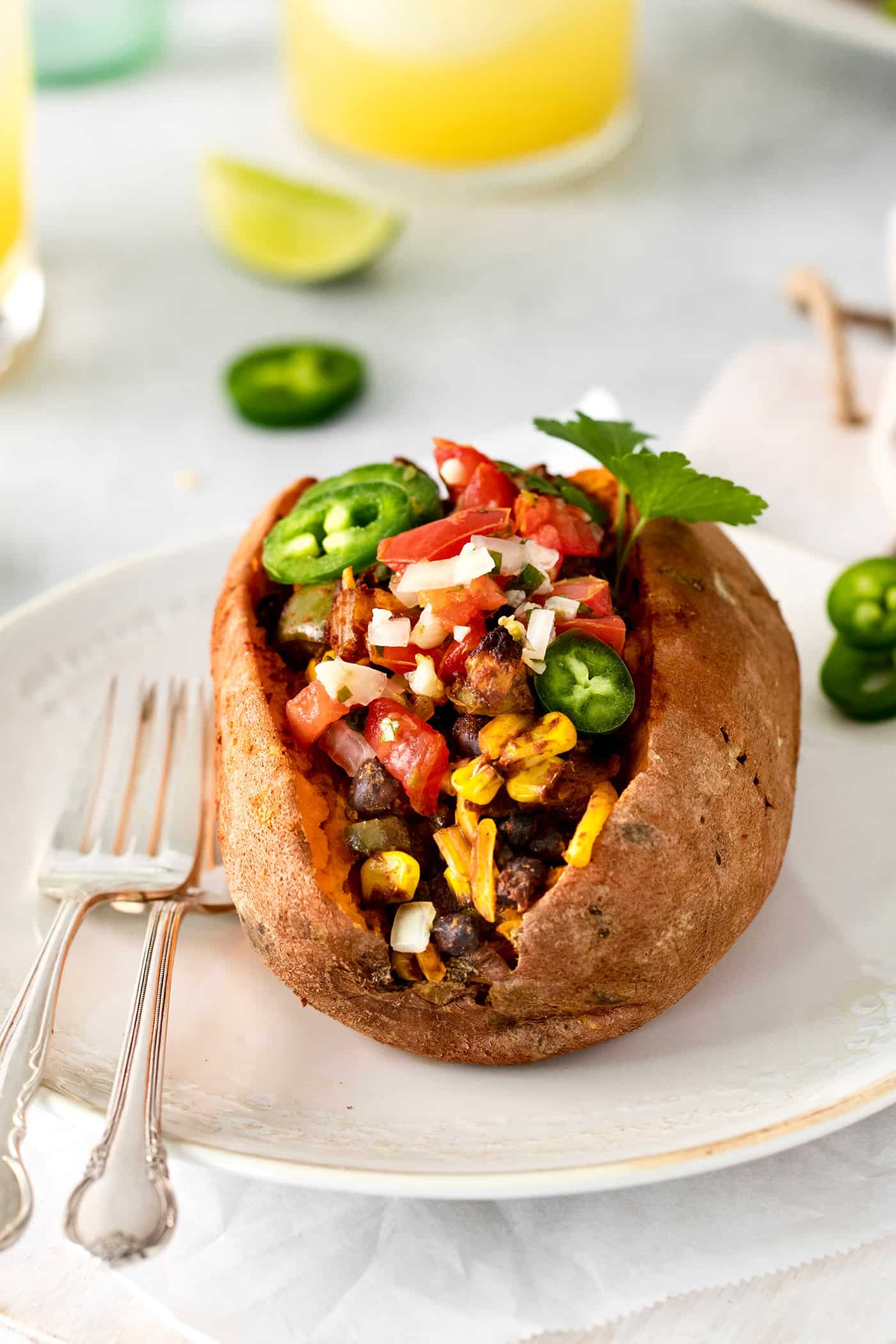 Angled view of a taco stuffed sweet potato on a white plate