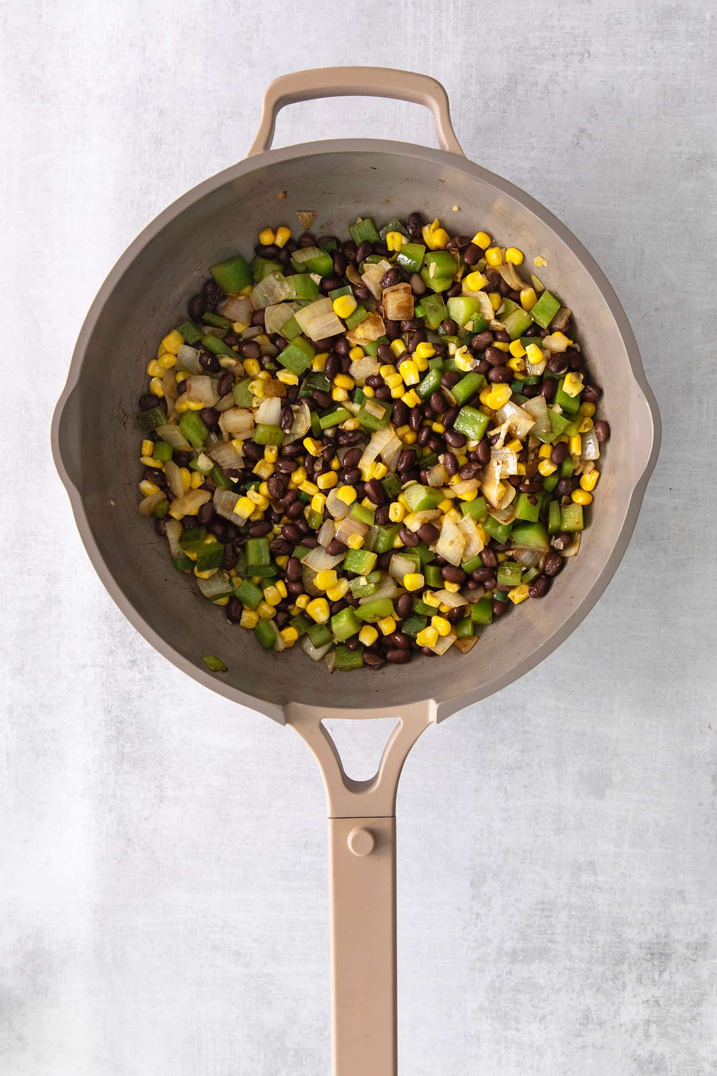 Peppers, onions, black beans, and corn in a skillet