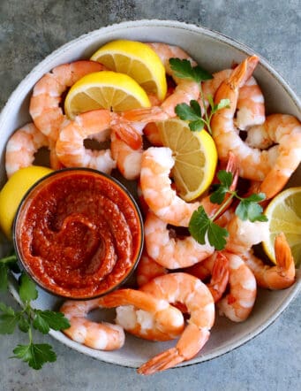 Overhead view of a bowl of shrimp with a dish of cocktail sauce