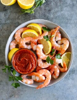 Overhead view of shrimp and lemon with a dish of cocktail sauce