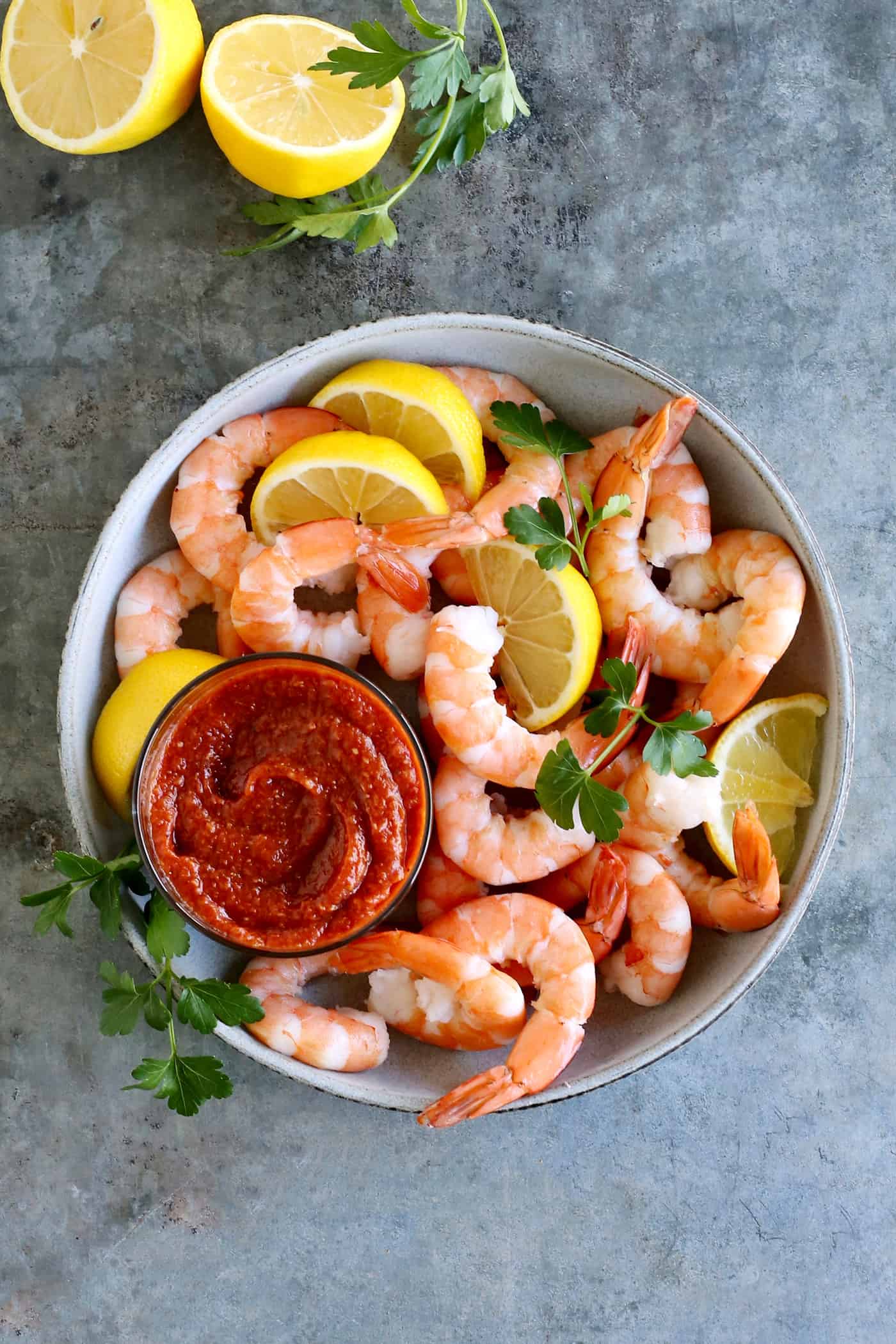 Overhead view of shrimp and lemon with a dish of cocktail sauce