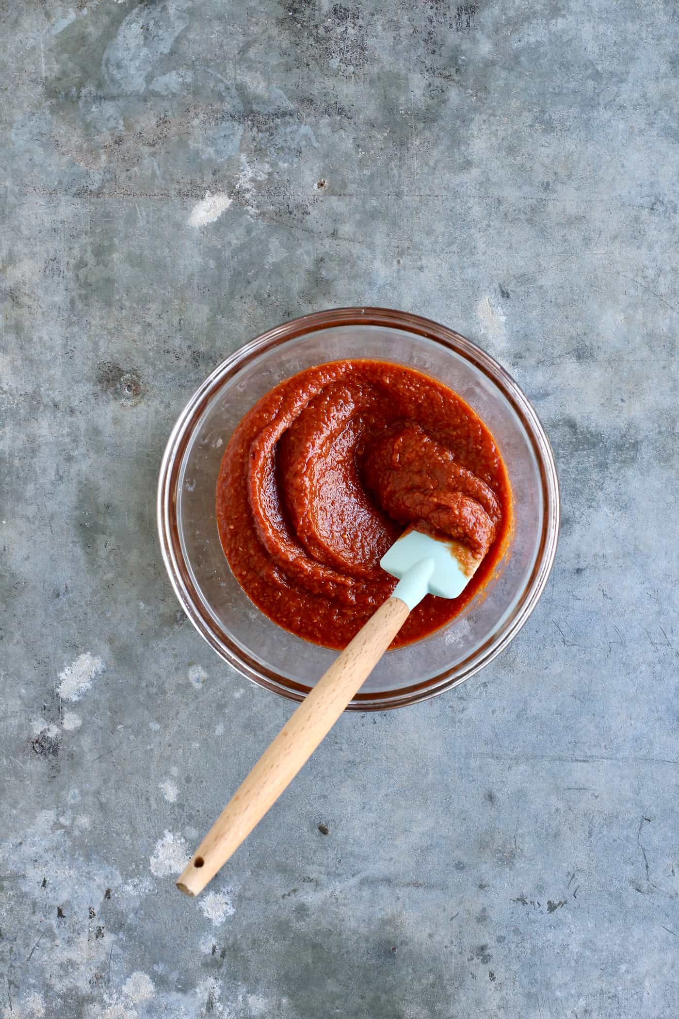 A spatula mixing shrimp cocktail sauce in a glass bowl