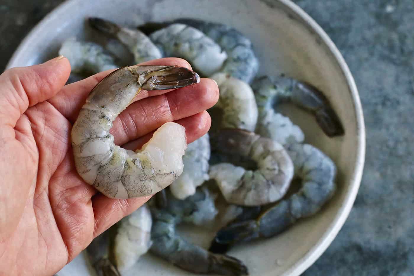 A hand holding a jumbo shrimp.