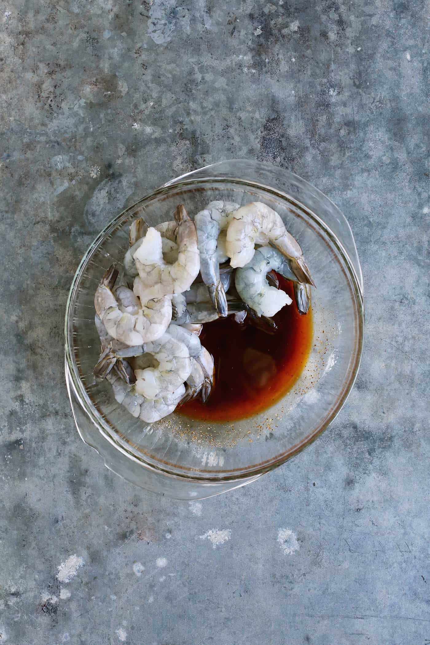 Raw shrimp and a marinade in a bowl.