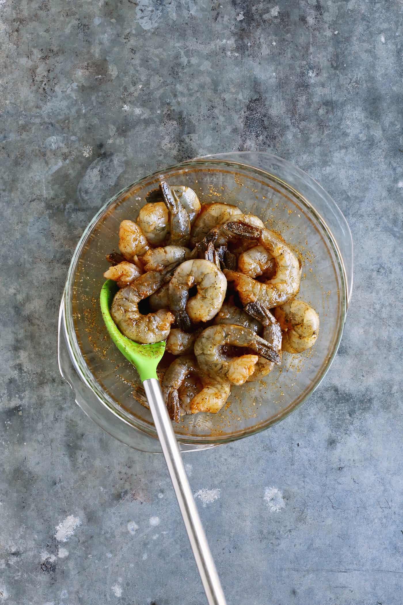Grilled shrimp coated with a marinade in a glass bowl