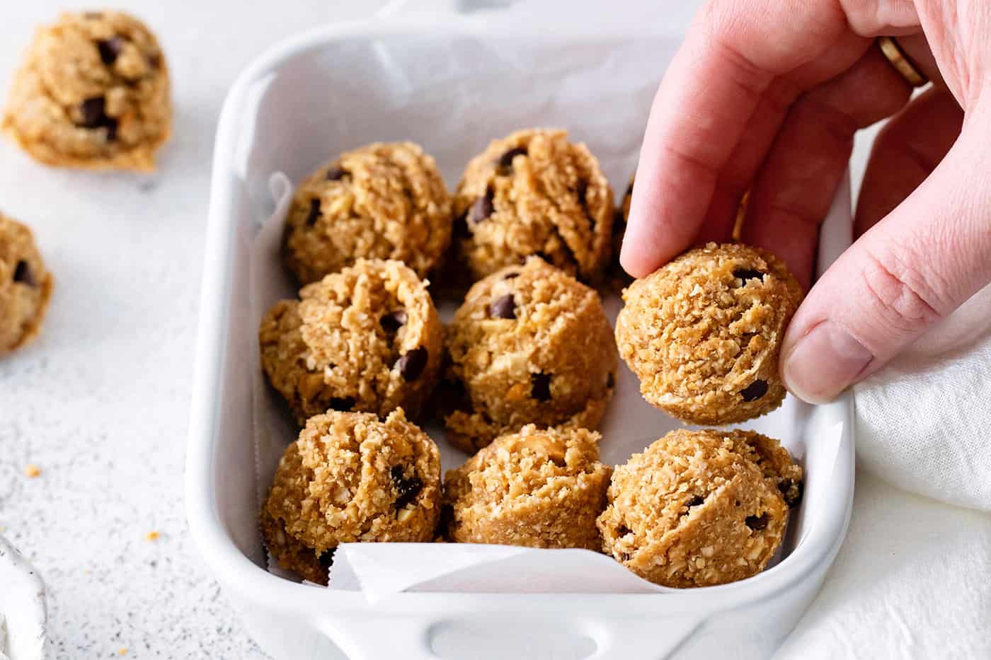 A hand reaching for peanut butter oat bites