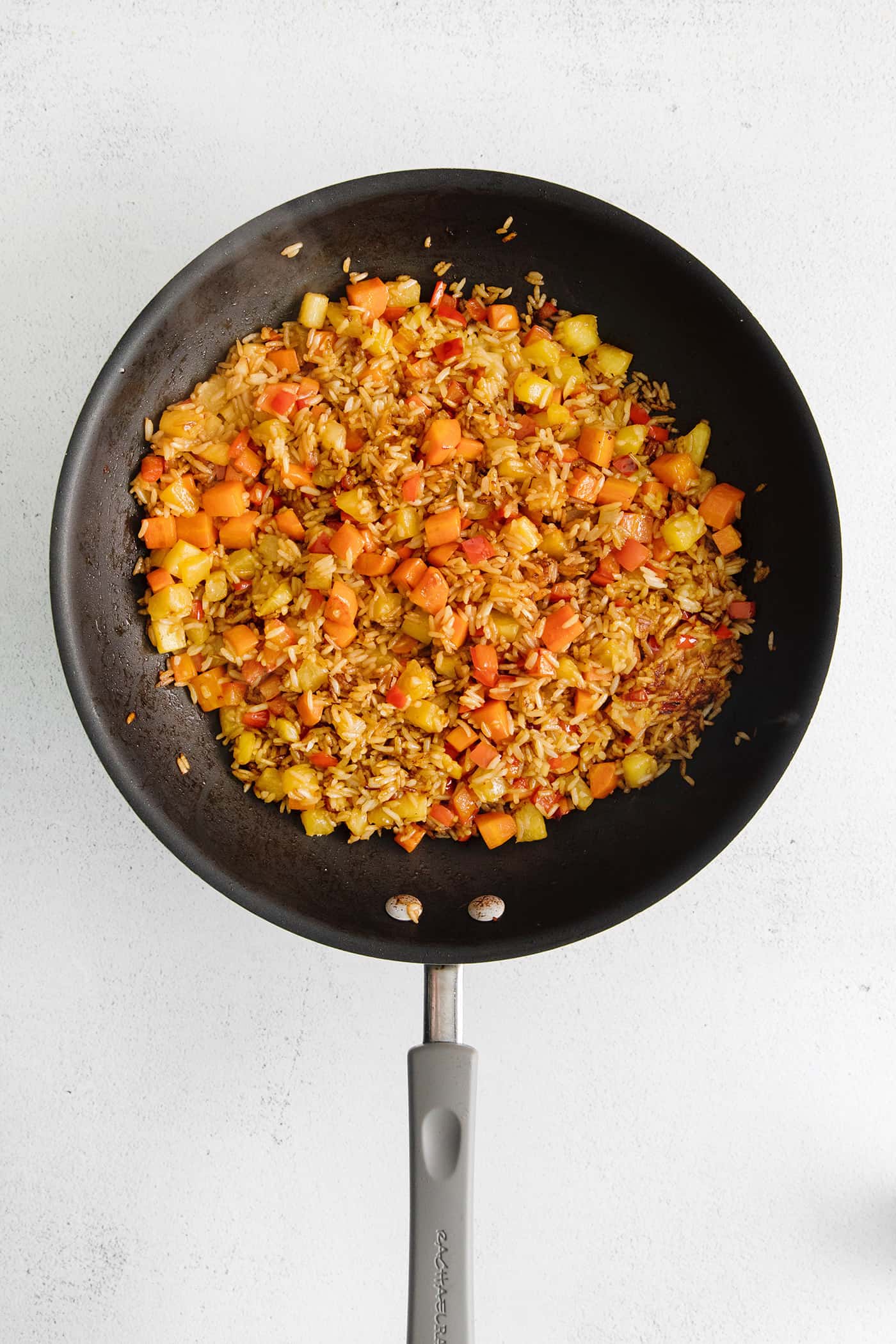 Pineapple, carrots, and bell peppers in a skillet