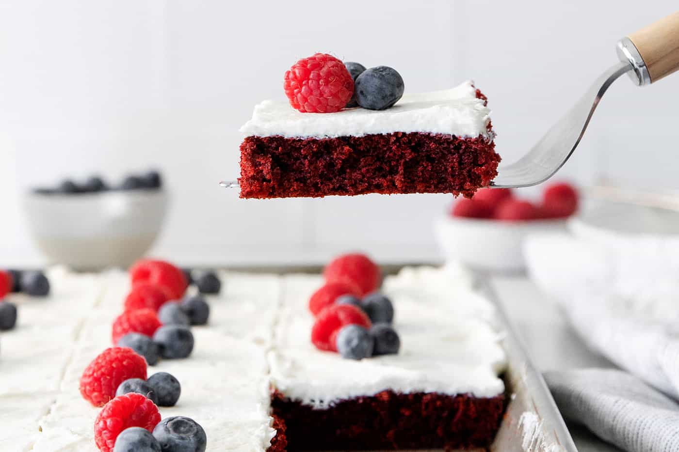 A spatula serving a slice of red velvet sheet cake