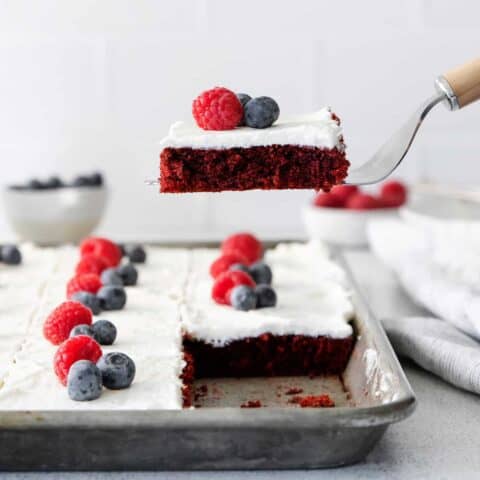 A spatula serving a slice of red velvet sheet cake