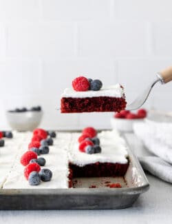 A spatula serving a slice of red velvet sheet cake