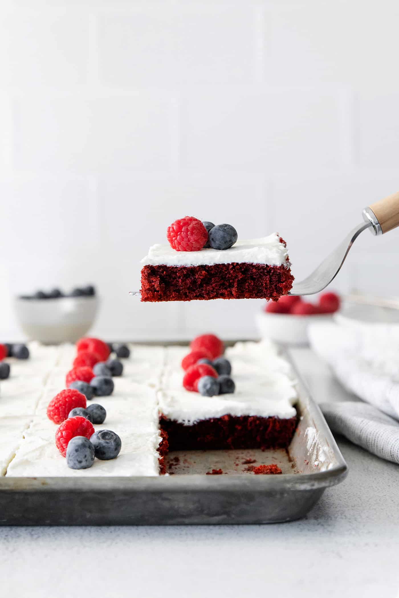 A spatula serving a slice of red velvet sheet cake