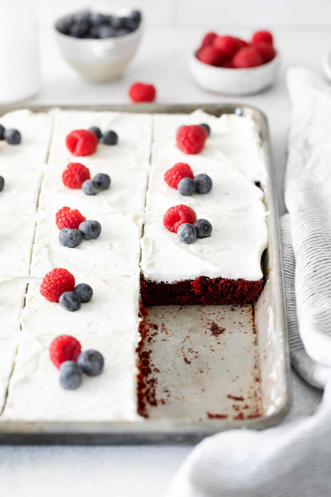 Angled view of a red velvet sheet cake with two slices missing