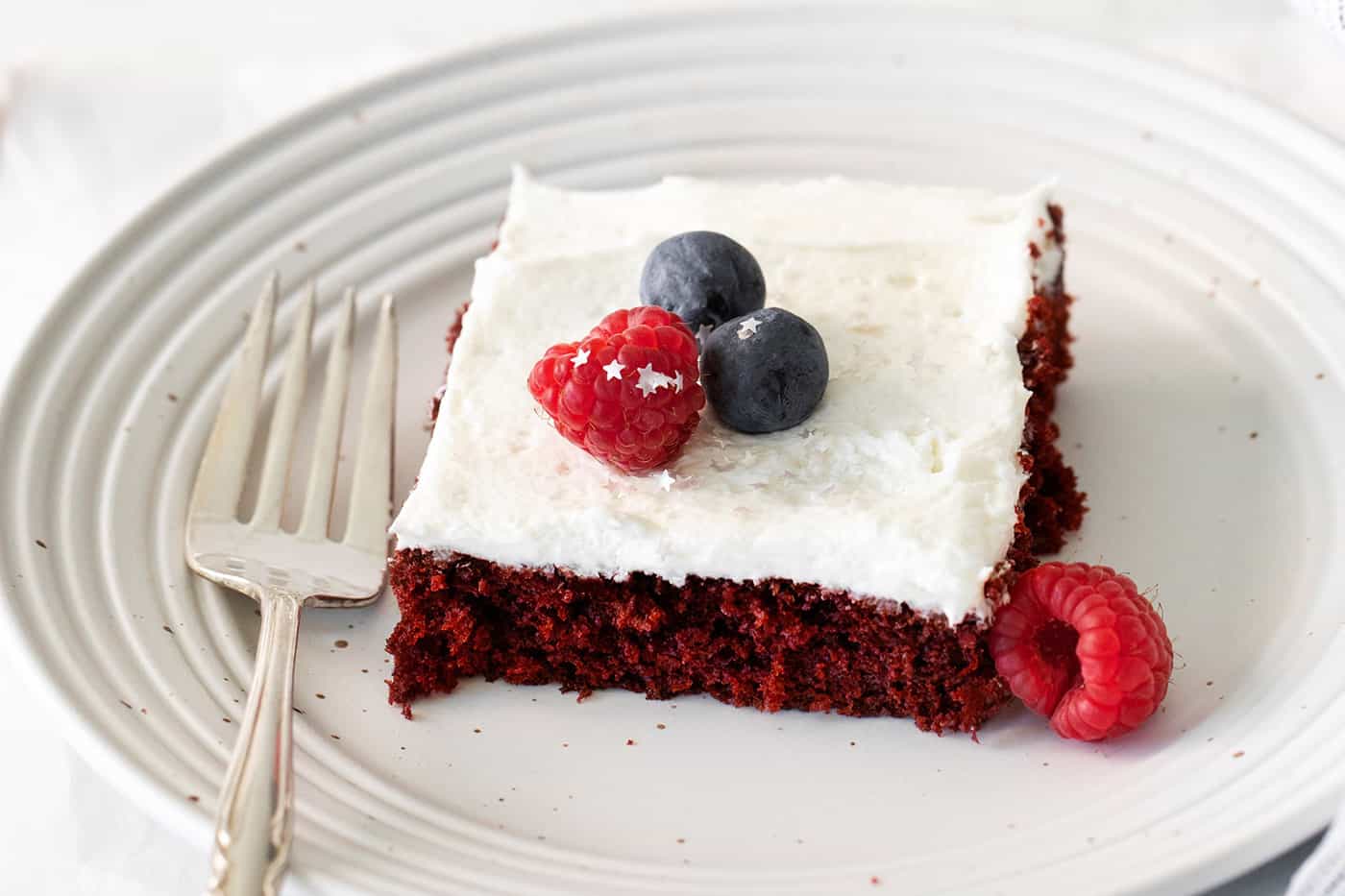 a piece of red velvet cake with fresh berries and star sprinkles