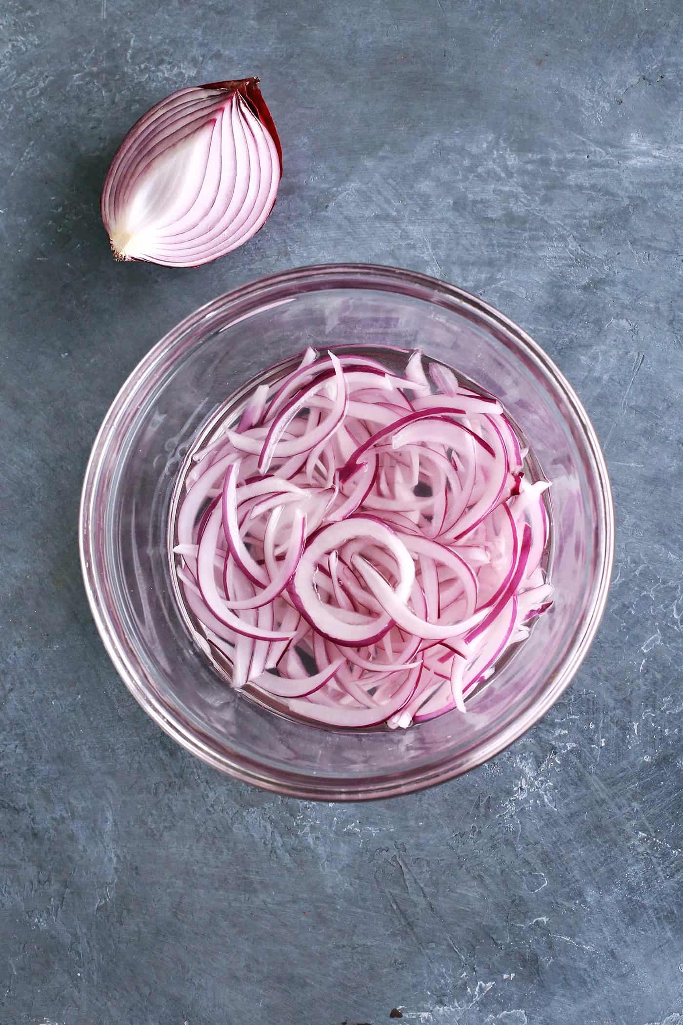 Sliced red onions in a bowl with vinegar