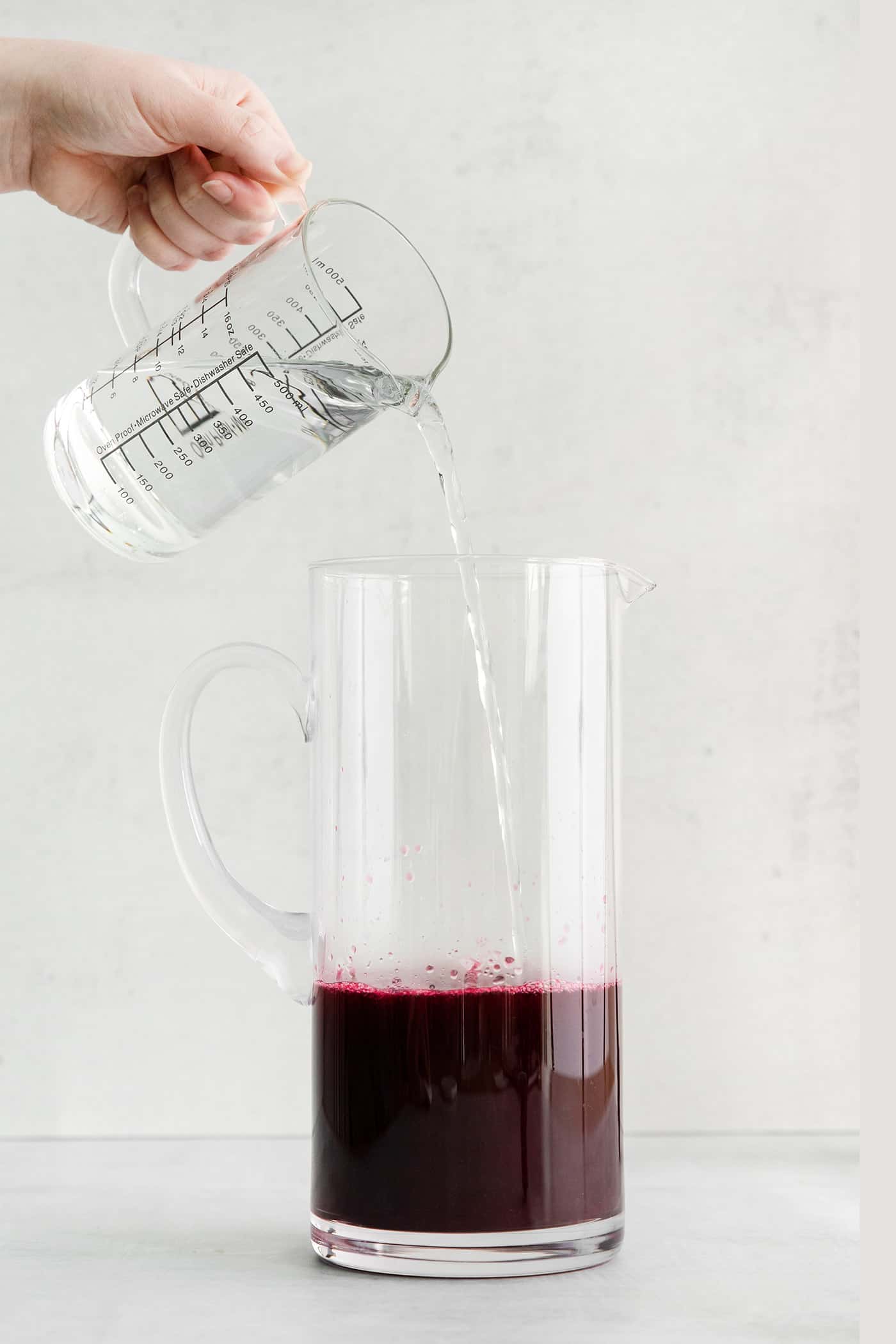 Water added to a pitcher with blueberry syrup