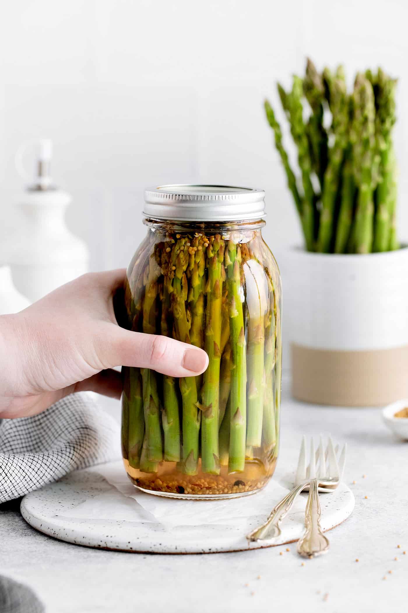 A hand grabbing a jar of asparagus