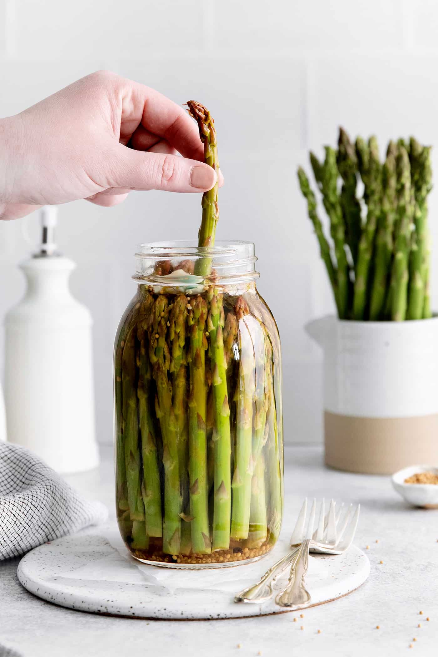 A hand pulling an asparagus from a jar