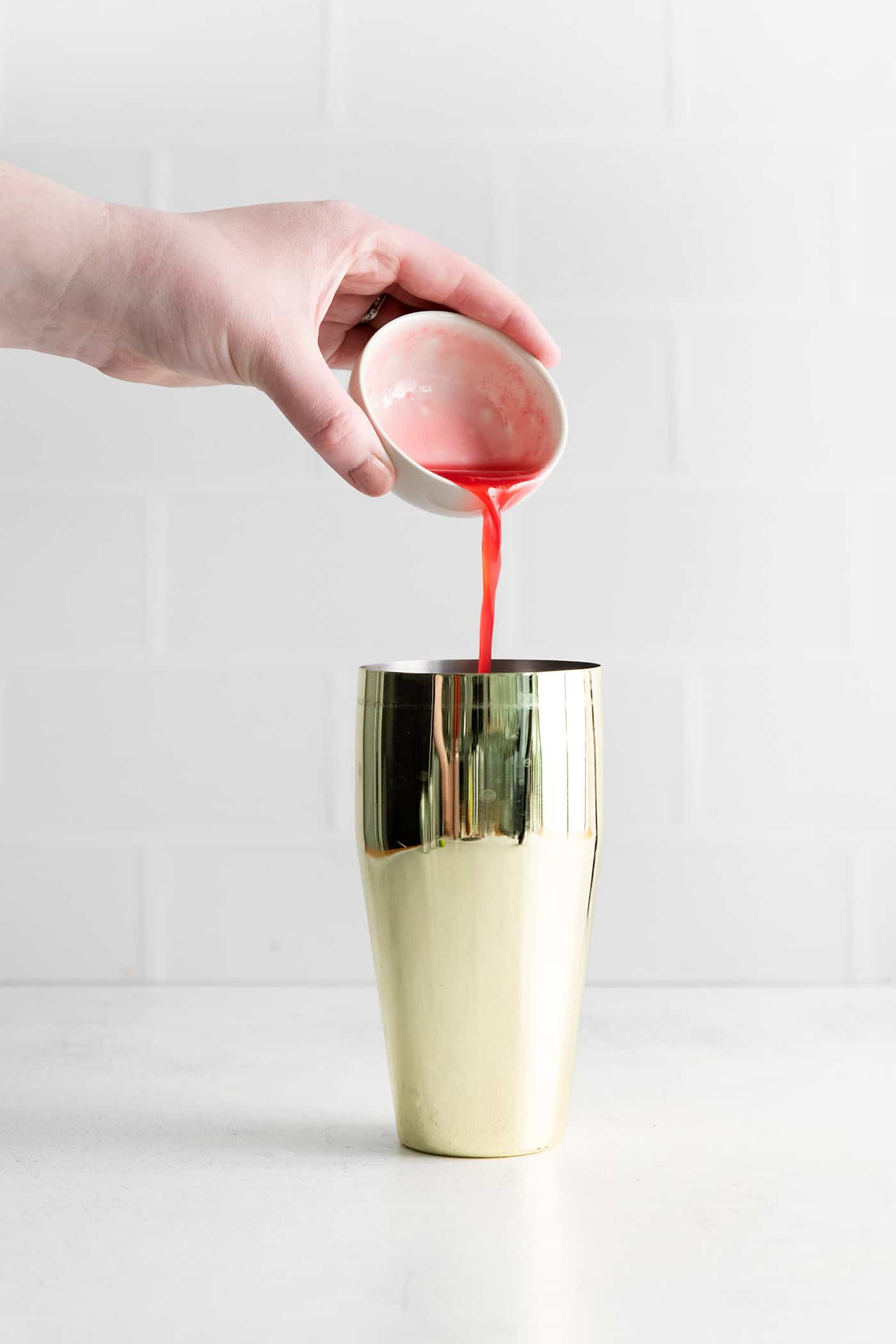 Raspberry rhubarb syrup being added to a shaker