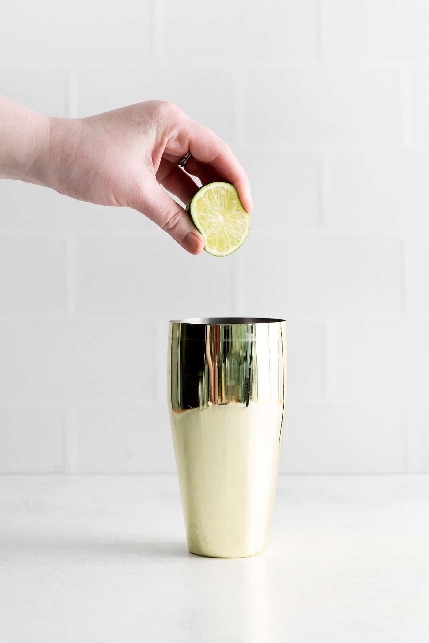 A lime being squeezed into a shaker