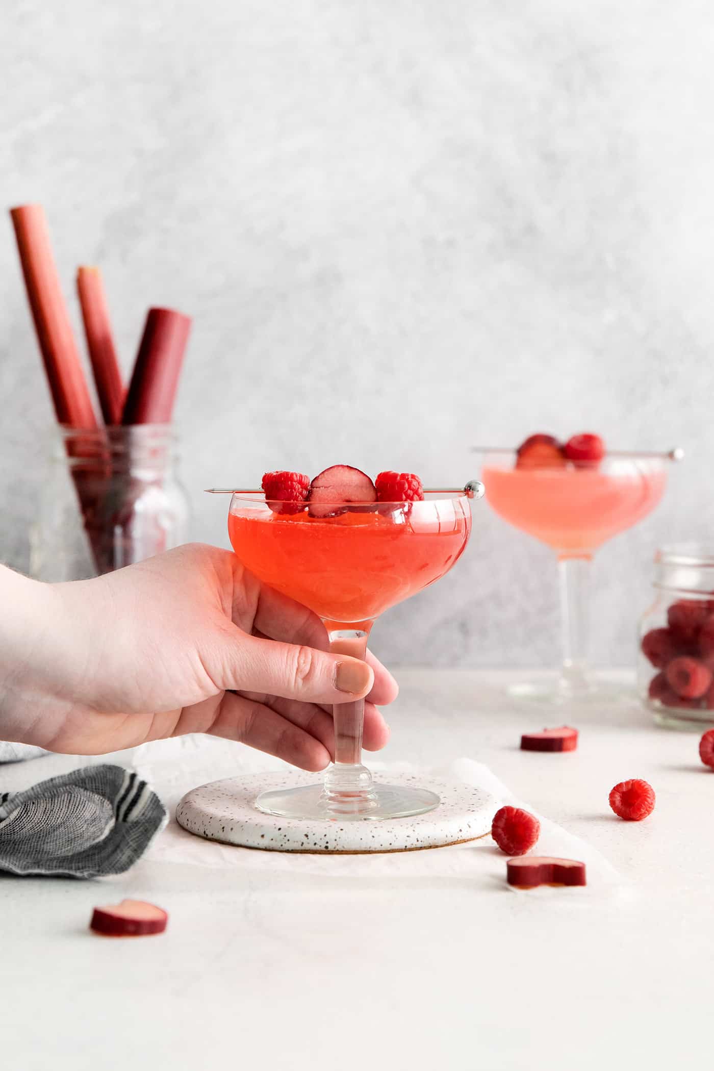 A hand grabbing a raspberry rhubarb cosmopolitan