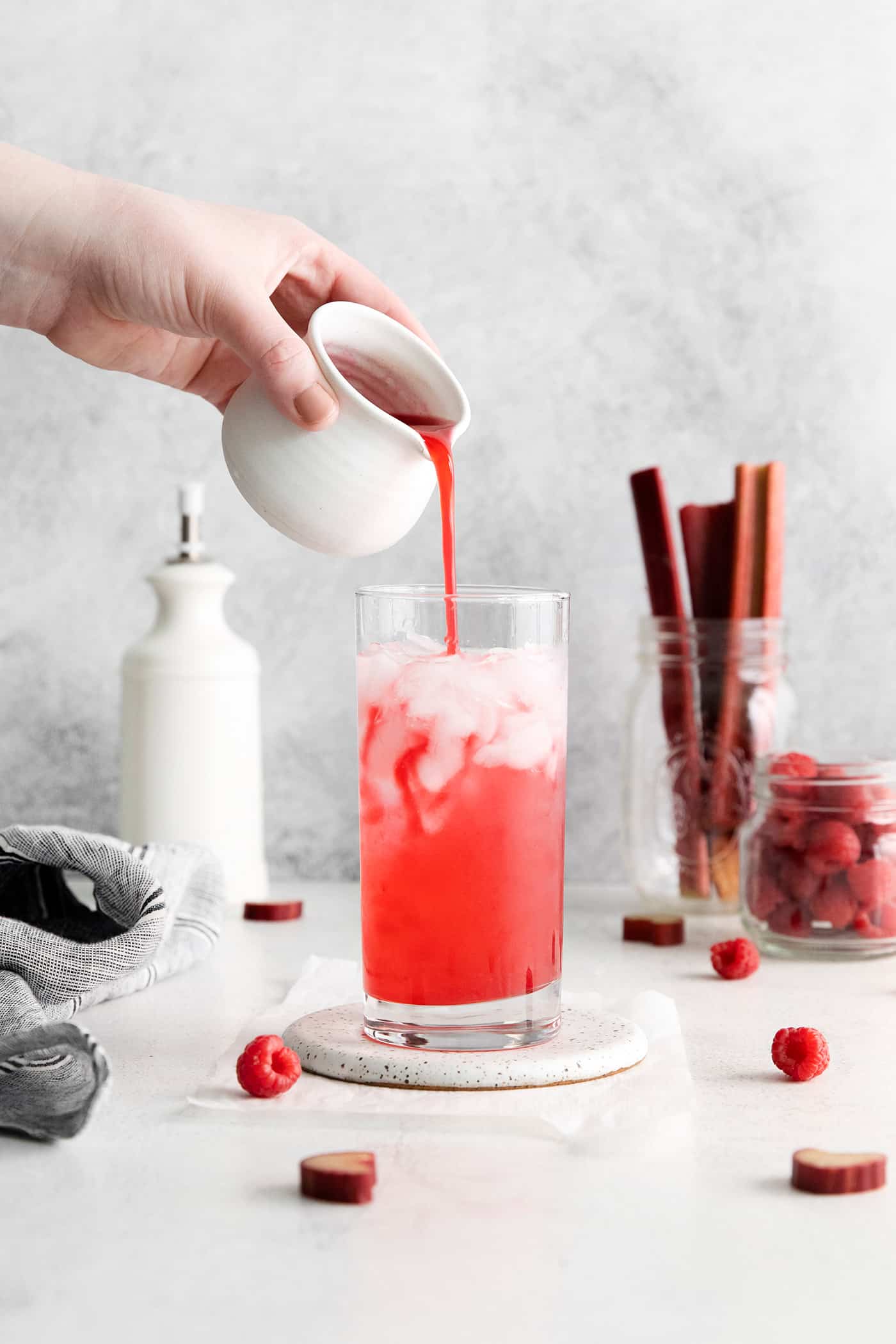 Raspberry syrup being poured into a glass with club soda